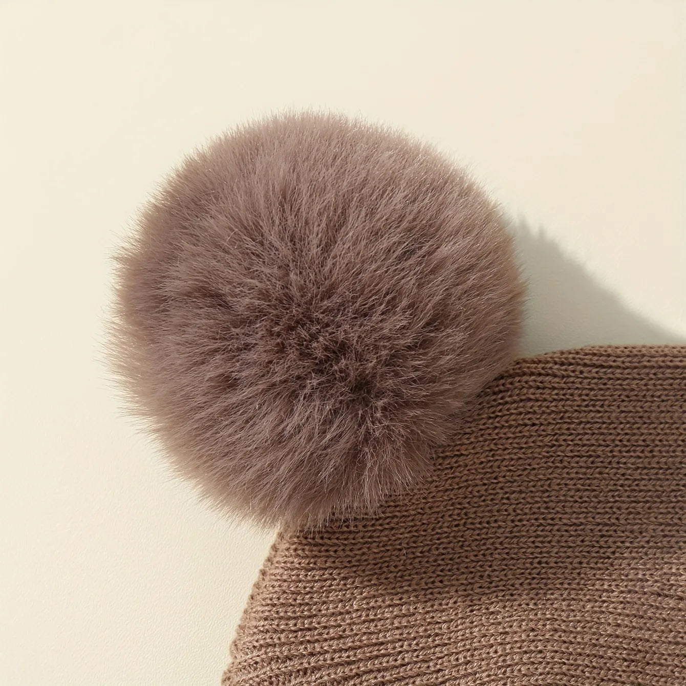 Gorro de lã em cor sólida, ideal para recém-nascidos. Com pompom, é perfeito para o inverno, mantendo os pequenos aquecidos. Disponível para crianças de 0 a 3 anos.